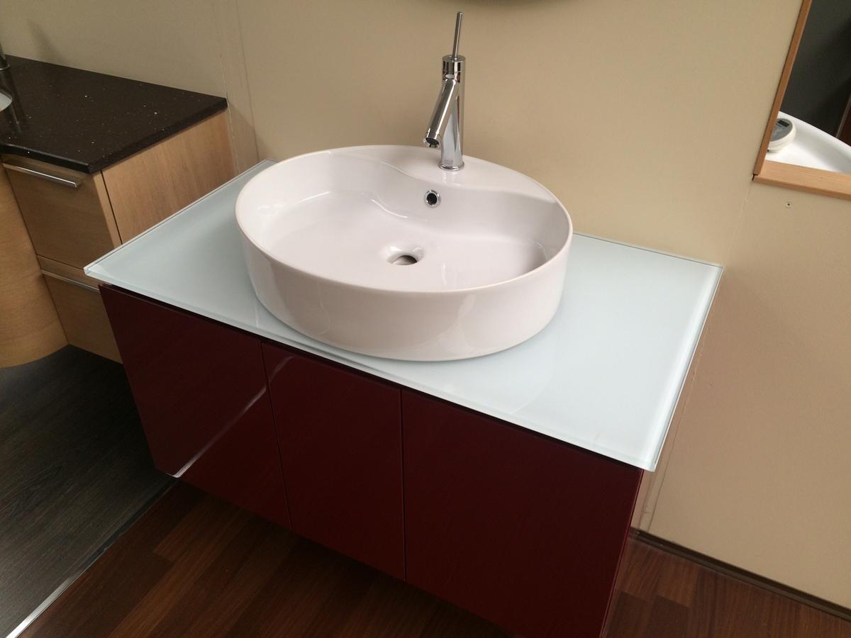 Nell'immagine si vede un mobile bagno laccato rosso, top in cristallo, lavabo da appoggio